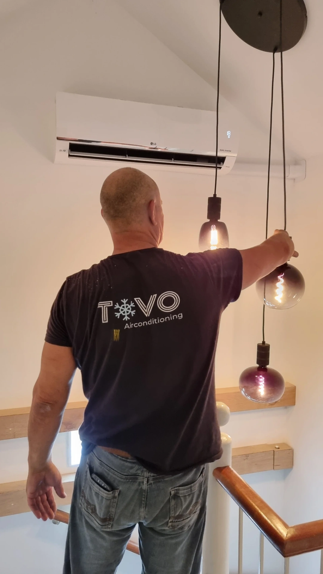 Tovomontage monteur — rug met TOVO Airconditioning logo, kijkend naar geïnstalleerde LG airco